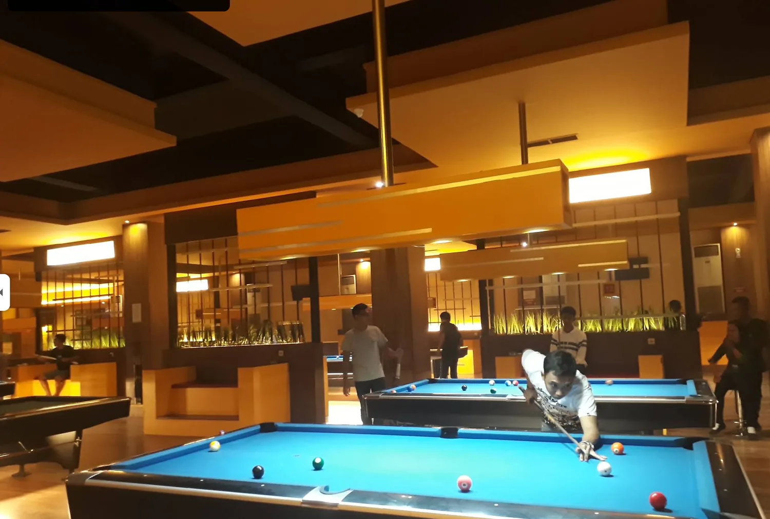 Deretan meja biliar berkain biru di dalam POCKET Family Sport Billiard